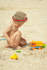 cute little boy play with sand on beach