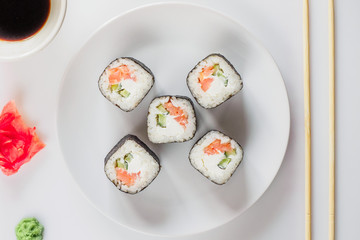 Roll of sushi on a plate, Sushi roll on a tablet on the table restaurant / eating sushi roll using chopsticks, white background, Sushi roll and hand with chopsticks. Japanese food.