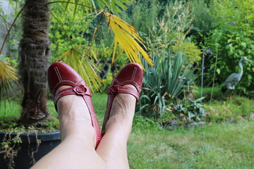 Frau mit roten Schuhen relaxt im Garten