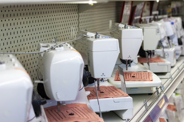 Electric sewing machines on store shelf, side view, shallow depth of field.