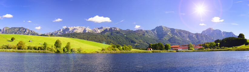 Panorama Landschaft in Bayern mit Alpen im Allgäu und Spiegelung im Forggensee