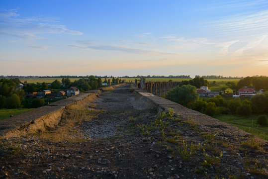 old concrete arch bridge near the village at sunset of the day
