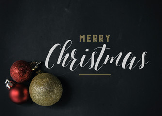 Cheerful Merry Christmas text on blackboard background for holiday graphic or banner.  Including red and gold ornaments with message.
