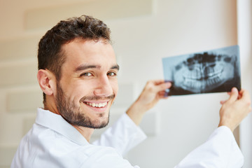 Dentist smiling and holding x-ray