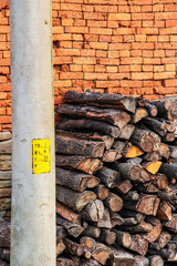Stacked firewood next to a rustic brick fence and an electric pole in the Bulgarian village of Debnevo