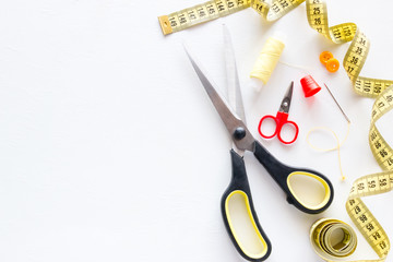 sewing accessories scissors, measuring tape, thread, needles on white background with place for text