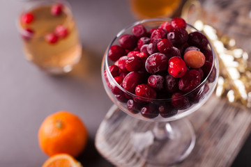 Ripe cranberries in glass vase on grey background. Selective focus