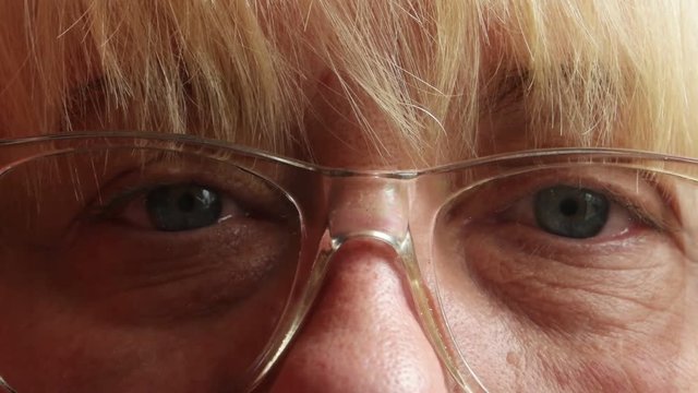 Middle-aged woman in glasses is looking at the camera. Blue eyes of the middle-aged woman,   close-up