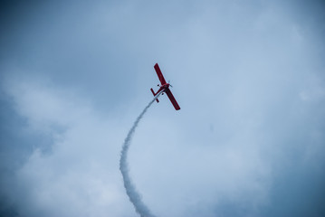 Single light airplane leaving its trail in the dramatic blue sky with clouds