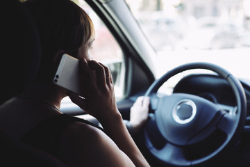 Rear view of woman in the car talking on mobile phone while driving