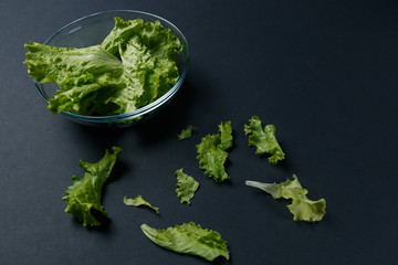 fresh salad leaves in bowl on dark background. Top view