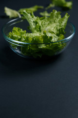 fresh salad leaves in bowl on dark background. Top view
