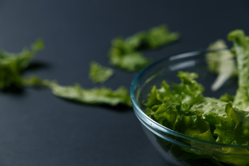fresh salad leaves in bowl on dark background. Top view