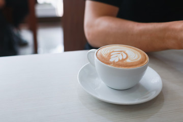 Hot Coffee latte  at indoor cafe with man background