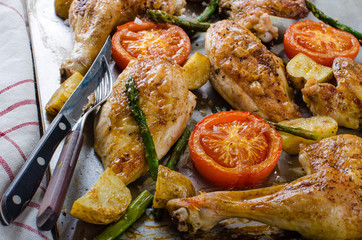 Oven-baked chicken with vegetables on the roasting tray