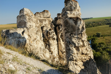 Beautiful scenery, chalk mountains stick out of the earth against the background of blue sky and green grass.