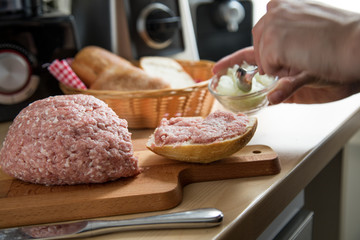 Frau belegt Mett Brötchen mit Zwiebeln für deftige Deutsche Brotzeit
