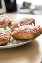 Teller mit 5 Mettbrötchen mit Schweinemett und Zwiebeln auf Küche Arbeitsfläche