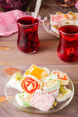 Traditional Turkish Delight. on a saucer and hot karkade in cups on a wooden table