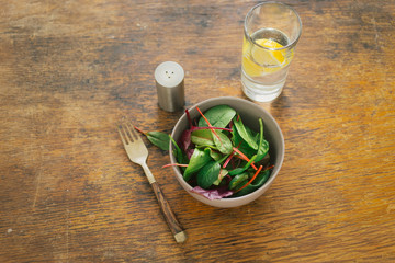 Bowl fresh salad chard spinach leaves glass water lemon