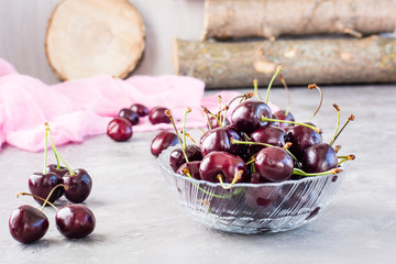 Ripe fresh sweet cherries  in a glass bowl on a gray background