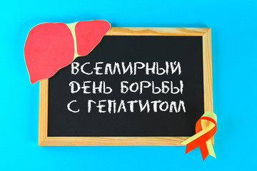 Inscription in Russian World Hepatitis Day. June 28th. Chalkboard, liver and red yellow ribbon on a blue background.