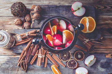 Red apples and oranges in red wine. Recipe for traditional winter mulled wine. Spices and cinnamon. Wooden rustic background