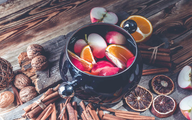 Red apples and oranges in red wine. Recipe for traditional winter mulled wine. Spices and cinnamon. Wooden rustic background