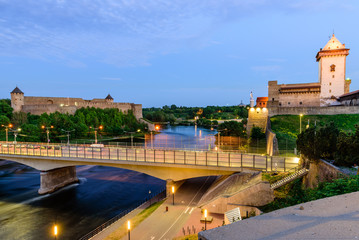 Beautiful night view of Narva Castle with tall Herman's tower and the ancient Russian fortress in Ivangorod, the monument and popular tourist attraction on the border with Estonia, Narva, Estonia