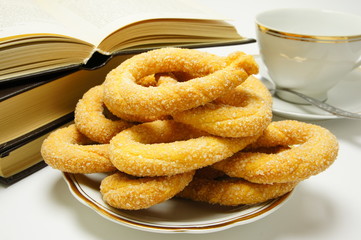 Breakfast. Sweet biscuits next to the book and a cup.