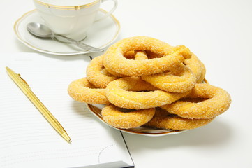 Breakfast. Sweet biscuits next to the cup and diary.