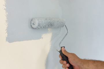 Painting and decorating an interior wall with a roller and modern light grey paint