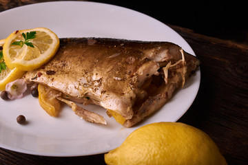 Grilled fish with herbs and lemon on wooden background. Mediterranean luxurious seafood concept