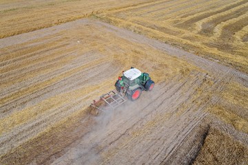 Tractor plowing field after harvesting.