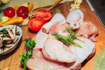 crude chicken meat on a kitchen table, vegetables and kitchen accessories lie nearby