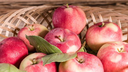 Ripe red apples with leaves in a basket. Autumn harvest. Close-up