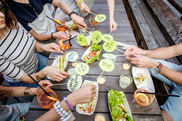 People holding plates with healthy food slogans on the table background full of tasty snacks...