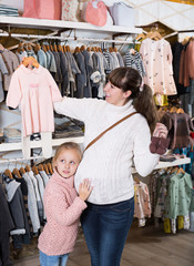 Fototapeta na wymiar Mother and small daughter choosing clothes for baby