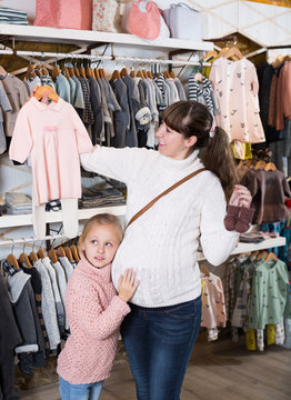 Mother and small daughter choosing clothes for baby
