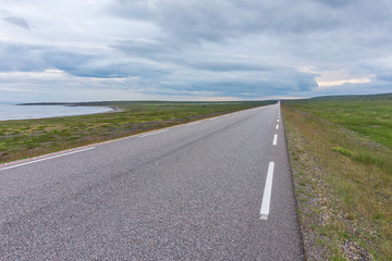 The road stretches into the distance on a background of green meadows