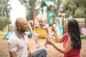 Cute adorable baby girl playing and swinging in swing in park