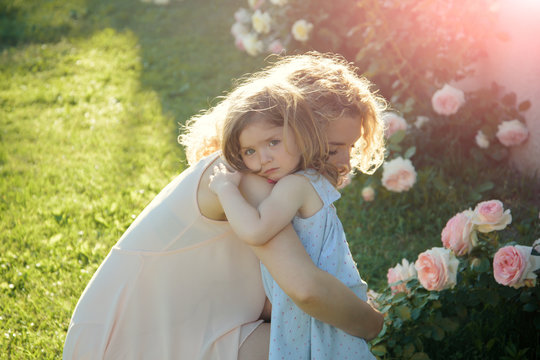 Woman with girl child at blossoming rose flowers