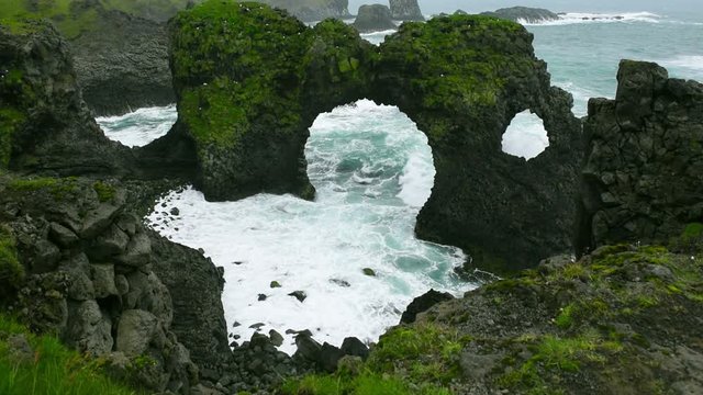 Arnarstapi Arch near Arnarstapi Village at the south Iceland, wave splashing through the hole in rocks