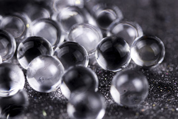 Crystal Gel water balls on dark black glitter texture rotation. Close up macro footage.