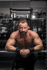 Fototapeta na wymiar Hombre fuerte con grandes músculos mirando de frente en el gimnasio.