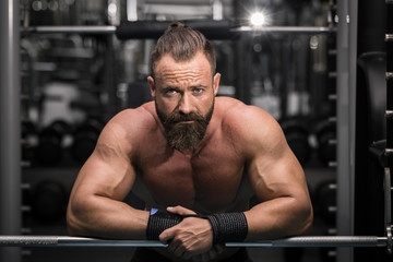 Fototapeta na wymiar Hombre fuerte con grandes músculos mirando de frente en el gimnasio.