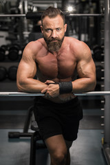 Fototapeta na wymiar Hombre fuerte con grandes músculos mirando de frente en el gimnasio.