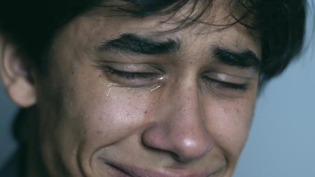 Sad desperate young man crying looking at camera- macro