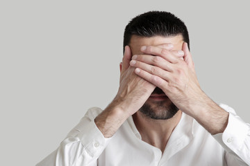 
Studio portrait of young man covering his eyes - see no evil concept