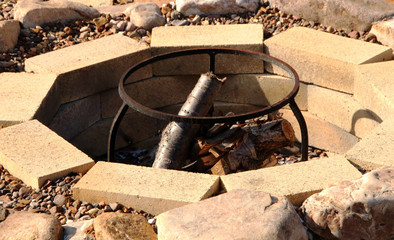 Fire pit with fuelwood surrounded by pebble in the summer garden